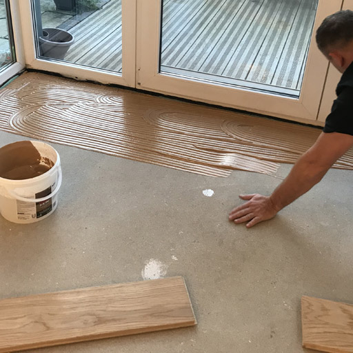 Dielenkleber auftragen, um Dielen auf Estrich zu verkleben
