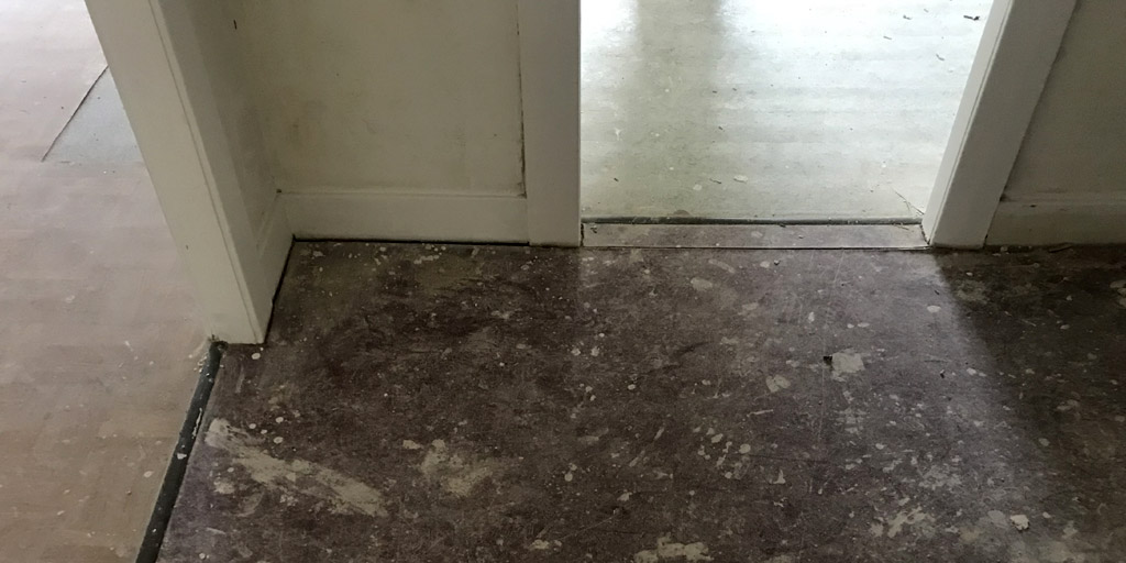 Verschiedener Belag aus PVC klebt auf den Dielen.