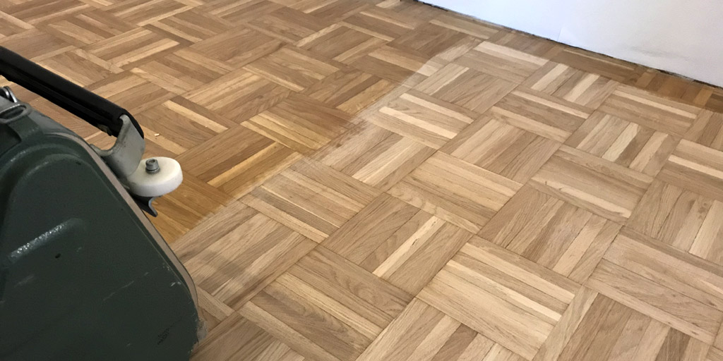 Einen Parkettboden zu färben, ist auch ohne Schleifen möglich. Das Parkett wird dann maschinell zur Vorbereitung gereinigt.
