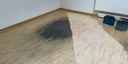 Abgenutzten Parkettboden auffrischen: Mosaikparkett in englischem Verband mit einem schwarzen großen Flec0, der zum Teil abgeschliffenen ist