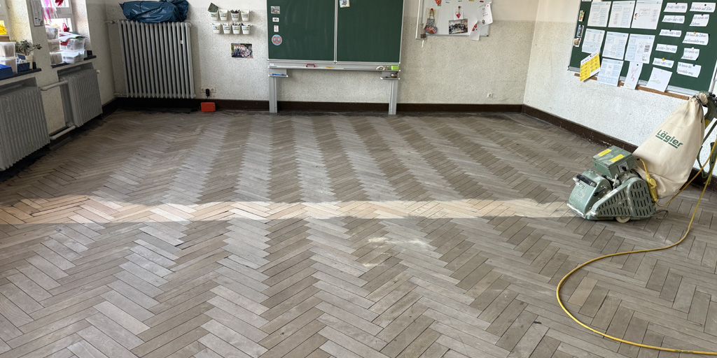 Parkett vor dem Lackieren schleifen: Der Grobschliff zeigt, wie verschmutzt der Boden war.