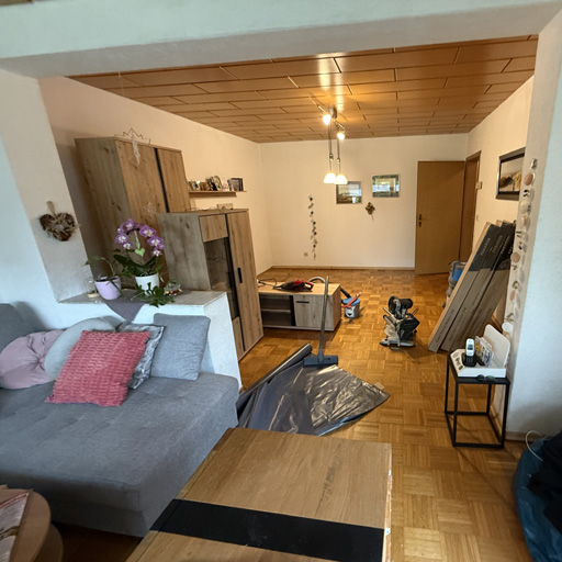 Möbliertes Wohnzimmer mit beschädigtem Parkett