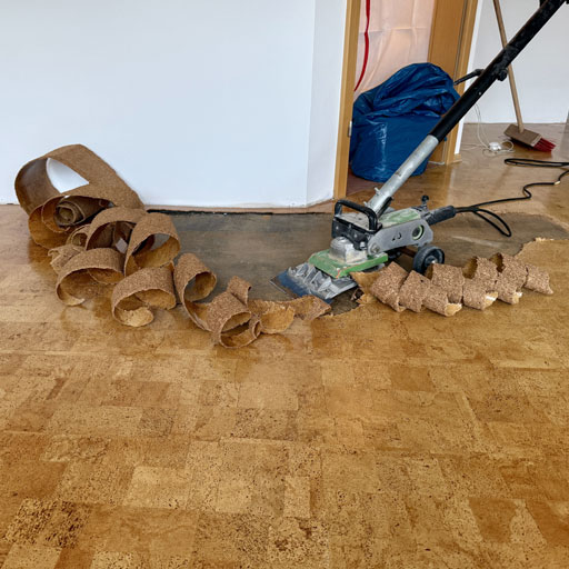 Korkboden im Wohnzimmer mit dem Teppichstripper lösen.